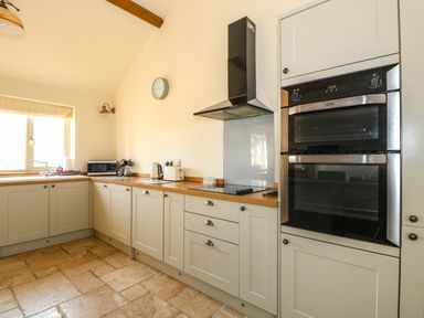 A kitchen with built in oven microwave kettle toaster and stovetop at Sunnyside Cottage in Blackborough End near Kings Lynn