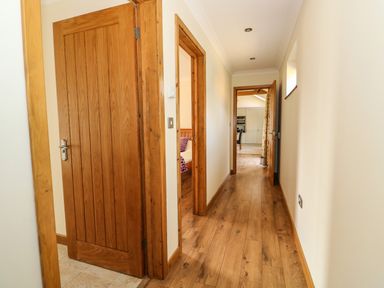A hallway with wooden floor and doors leading to a bedroom and kitchen at Sunnyside Cottage in Blackborough End near King's Lynn