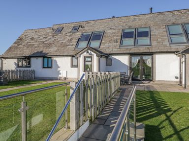 The exterior of a house with a ramp and lawn at Primrose Cottage in Aldingham