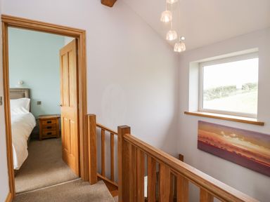 A hallway with wooden banister and a doorway leading to a bedroom at Primrose Cottage in Aldingham