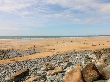 A sandy beach with scattered people and rocky foreground at Pound Cottage in Huntshaw near Great Torrington