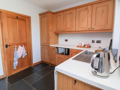 A kitchen with wooden cabinets and sink at Pound Cottage in Huntshaw near Great Torrington