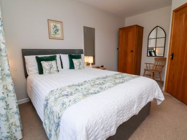 A bedroom with a bed and mirror at Pound Cottage in Huntshaw near Great Torrington