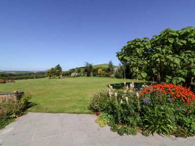 A garden with grass, trees, and flowers at Pound Cottage in Huntshaw near Great Torrington
