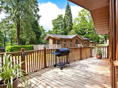 An outdoor deck area with a barbecue grill and a planter at Beech Hill Lodge (Beech Hill 9) at Fallbarrow Park, Bowness-on-Windermere
