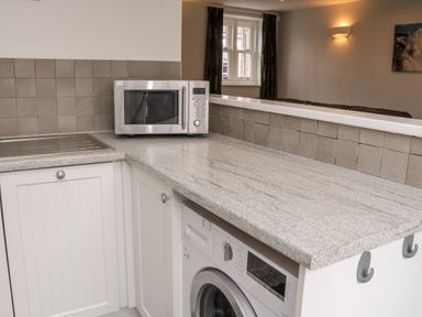 A kitchen countertop with a microwave oven and a washing machine at Razorbill Cottage in Whitby