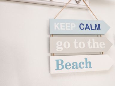 A hanging sign with the words keep calm go to the beach on a white wall at Razorbill Cottage Whitby