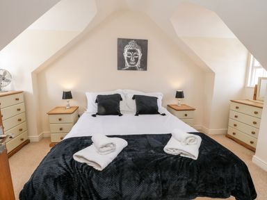 A bedroom with a bed black pillows towels lamps and dressers at Razorbill Cottage in Whitby