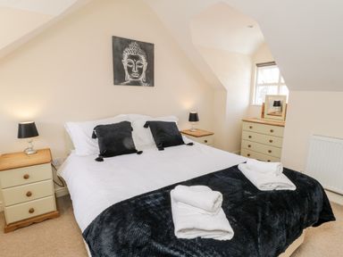 A bedroom with a double bed black pillows and lamps on bedside tables at Razorbill Cottage Whitby