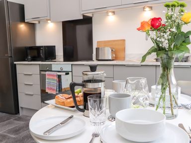 A kitchen with a round dining table set with dishes glasses and a vase of flowers at Lands Brow Lodge in Wigton