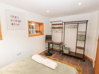 A bedroom with a bed and towels a black chair and a clothes rack with hangers at Lands Brow Lodge in Wigton