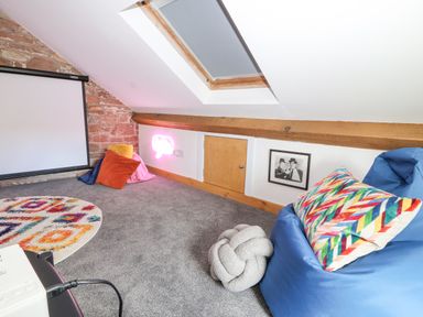 An attic room with a bean bag chair colorful pillow a round rug a projector screen and skylight at Lands Brow Lodge in Wigton