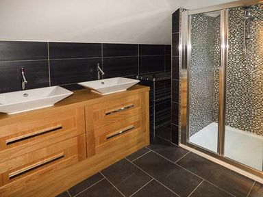A bathroom with two sinks on a wooden vanity and a shower with mosaic tiles at Treetops Govilon near Abergavenny