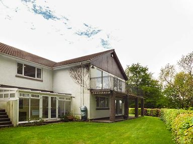 A two story house with a lawn and a balcony surrounded by trees at Treetops in Govilon near Abergavenny