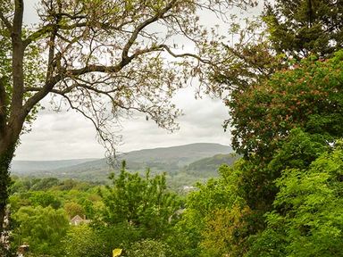 A landscape with trees and hills under a cloudy sky at Treetops in Govilon near Abergavenny