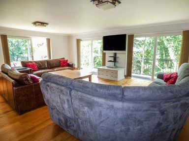 A living room with sofas a wooden coffee table and a wall-mounted television at Treetops in Govilon near Abergavenny
