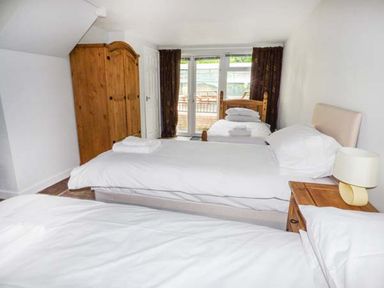 A bedroom with three beds a wooden wardrobe a bedside table and a lamp at Treetops Govilon near Abergavenny