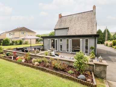 A house with a garden patio with outdoor furniture and plants at Pondfield Gate in Cwmgors