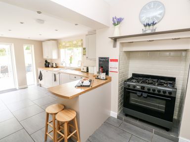 A kitchen with a stove oven wooden countertop stools and cabinets at Pondfield Gate in Cwmgors