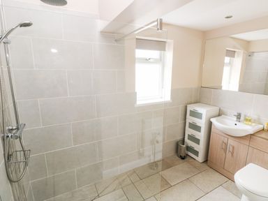A bathroom with a walk-in shower sink with cabinet and a small drawer unit at Pondfield Gate in Cwmgors