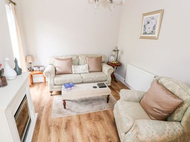 A sitting room with sofa armchair coffee table and fireplace at Pondfield Gate in Cwmgors