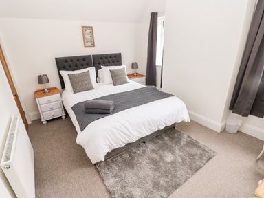 A bedroom with a double bed bedside tables lamps and a rug at Pondfield Gate in Cwmgors