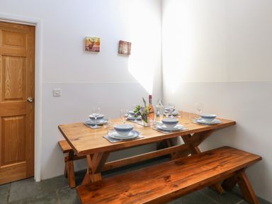 A dining area with a wooden table and benches set with plates glasses and a flower arrangement at The Long Barn in Morton on the Hill near Lenwade