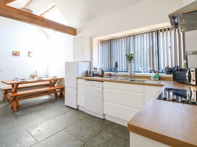A kitchen with white cabinets wooden countertops and a dining area with wooden benches at The Long Barn in Morton on the Hill near Lenwade