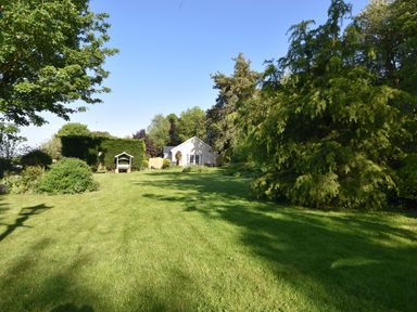 A large garden with green grass trees and a small white building at Lavender Cottage in Market Weighton