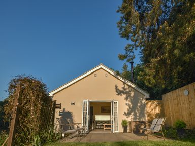 Garden with patio chairs and a cream house with open double doors at Lavender Cottage in Market Weighton