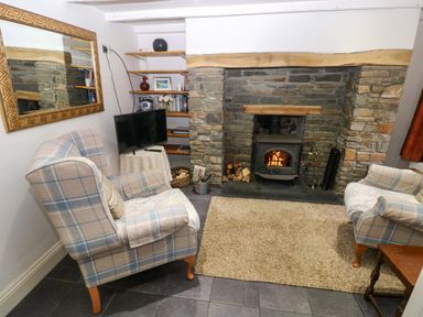 A living room with a fireplace and armchairs at Milk Wood Cottage in Laugharne