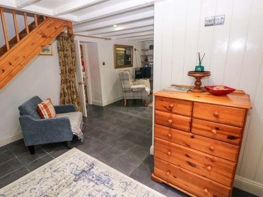 A living room with a chest of drawers and a chair at Milk Wood Cottage in Laugharne