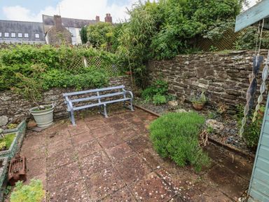 A garden with a bench and plants at Milk Wood Cottage in Laugharne