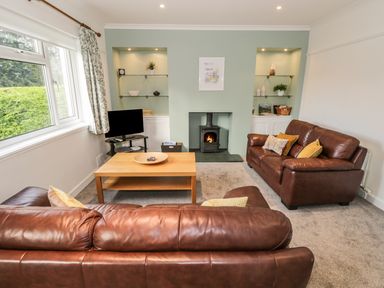 A living room with two brown leather sofas a wooden coffee table and a fireplace at Thompson Cottage in Ambleside
