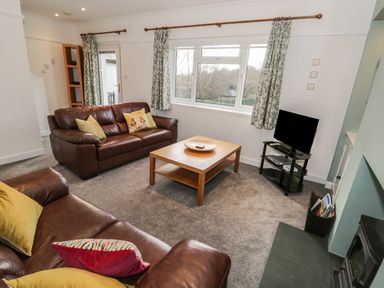 A living room with two leather sofas a wooden coffee table a television and patterned curtains at Thompson Cottage in Ambleside