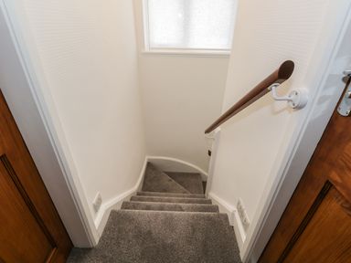A small staircase with carpet and a wooden handrail at Thompson Cottage in Ambleside