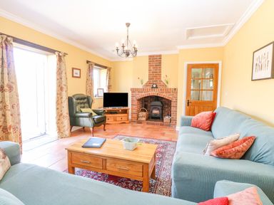 A living room with sofas a coffee table a fireplace and a chair at The Meadows Cottage Billingford near Bawdeswell