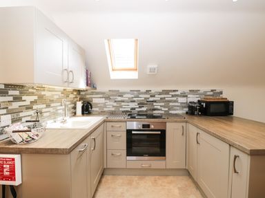 A kitchen with beige cabinets wooden countertops a built in oven a sink a microwave and a skylight at Shephard's Retreat in Charlton Mackrell near Somerton