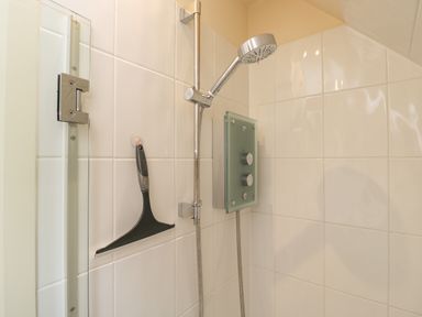 A shower area with a handheld showerhead mounted on a rail and a control panel on tiled walls at Shephard's Retreat in Charlton Mackrell near Somerton