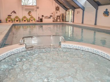 An indoor swimming pool with a smaller pool in the foreground green seats and wall decorations at High Tide in Rock