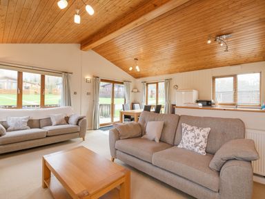 A living area with two sofas a wooden coffee table dining table and chairs and windows at High Tide in Rock