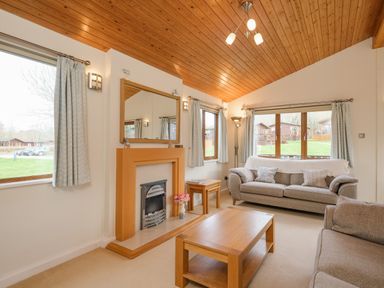 A living room with sofas coffee table fireplace and large windows at High Tide in Rock