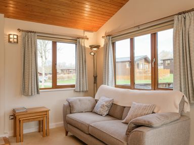 A living room with a sofa pillows small wooden tables and windows showing cabins outside at High Tide in Rock