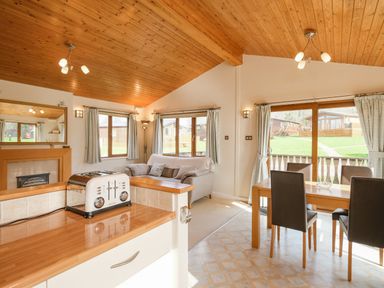 A living and dining area with a gray sofa wooden dining table black chairs and a toaster on the kitchen counter at High Tide in Rock