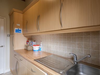 A kitchen countertop with a sink and faucet baskets and cleaning supplies on the counter at High Tide in Rock