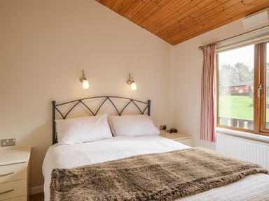 A bedroom with a double bed white bedding bedside tables and a window showing green grass at High Tide in Rock