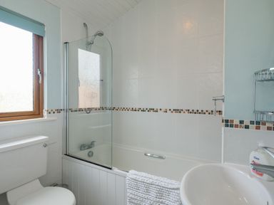 A bathroom with a bathtub shower combination a toilet a sink and a window at High Tide in Rock