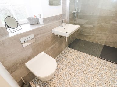 A bathroom with a wall-mounted toilet sink and walk-in shower at Blacksmith Cottage in Appleby-in-Westmorland