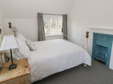A bedroom with a white bed near a window and a wooden side table at Bears Cottage in Bretforton near Broadway