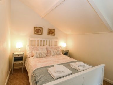 A bedroom with a double bed flanked by two bedside tables with lamps at Bridge Cottage in Aylsham
